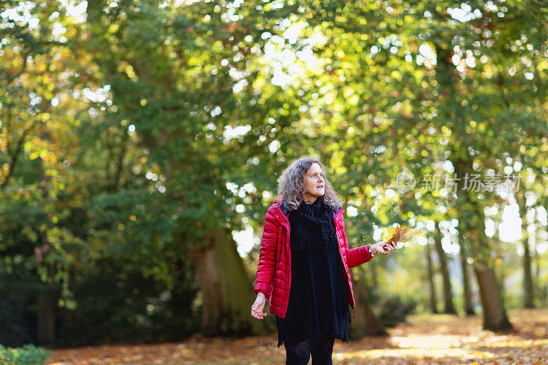 成熟的女人站在秋天的公园里