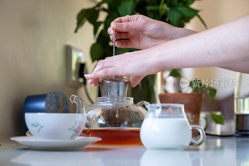 一个女人用茶叶泡了一壶新鲜的茶