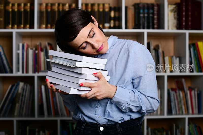 一个年轻女人睡在图书馆的书上