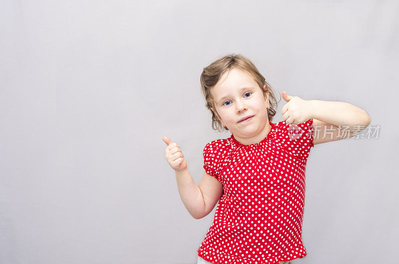 一个五岁女孩的肖像，金发白种人。孩子高兴地举起大拇指