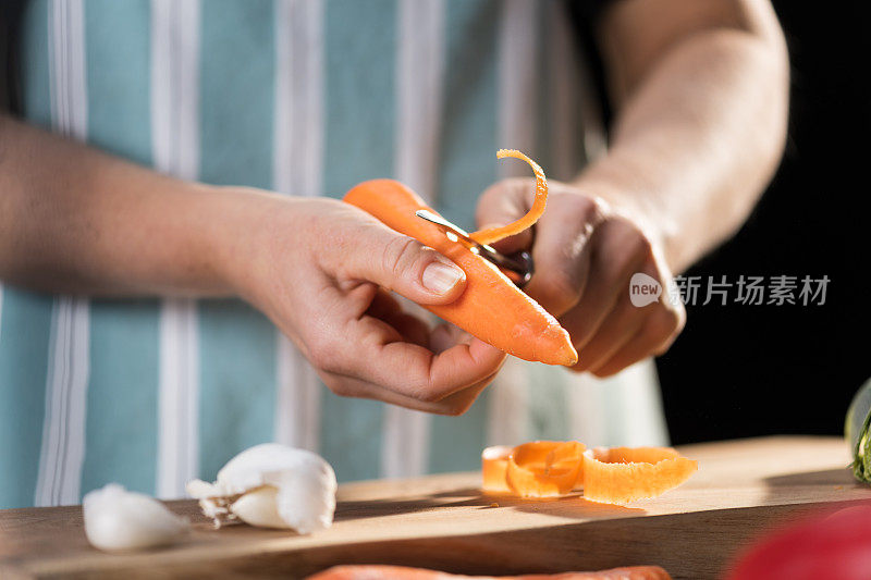 男子双手剥鲜橙胡萝卜。根菜厨房加工。