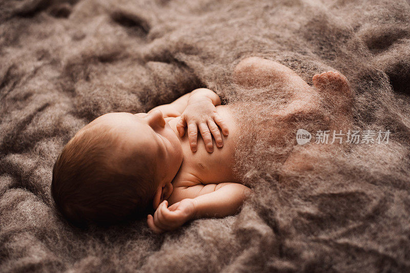 刚出生的婴儿睡在灰色的羊毛毯子上