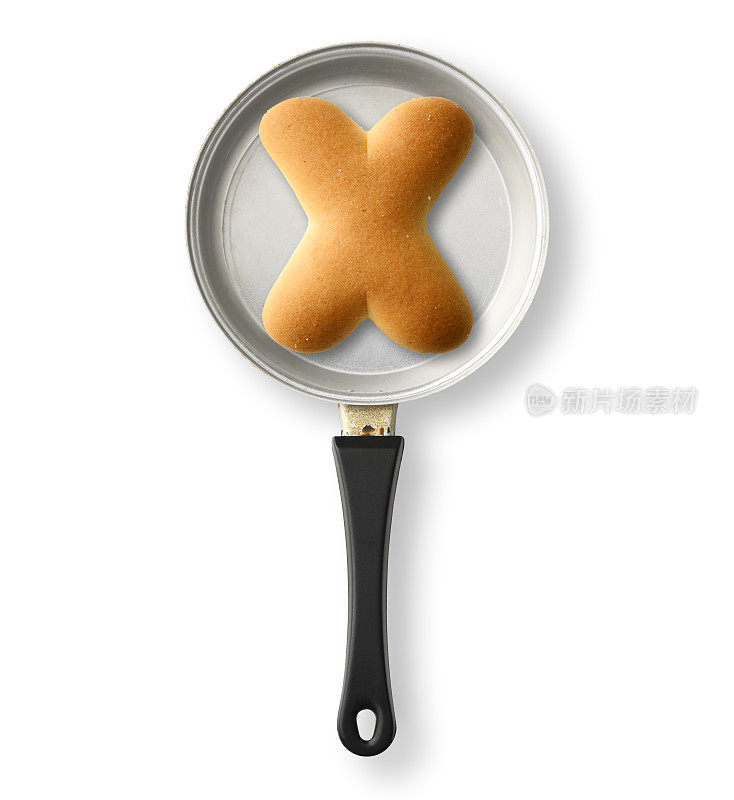 在白色背景上的一个旧玩具煎锅上的大写字母饼干X孤立的镜头