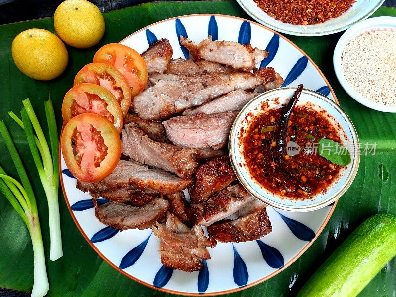 烤猪肉和辣酱(泰国菜)-绿叶背景。