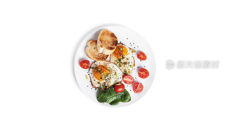 煎蛋、蔬菜和烤面包放在白色的盘子上，孤立在白色的背景上。美丽的早餐