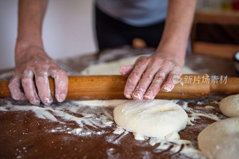 面包师用擀面杖揉面团