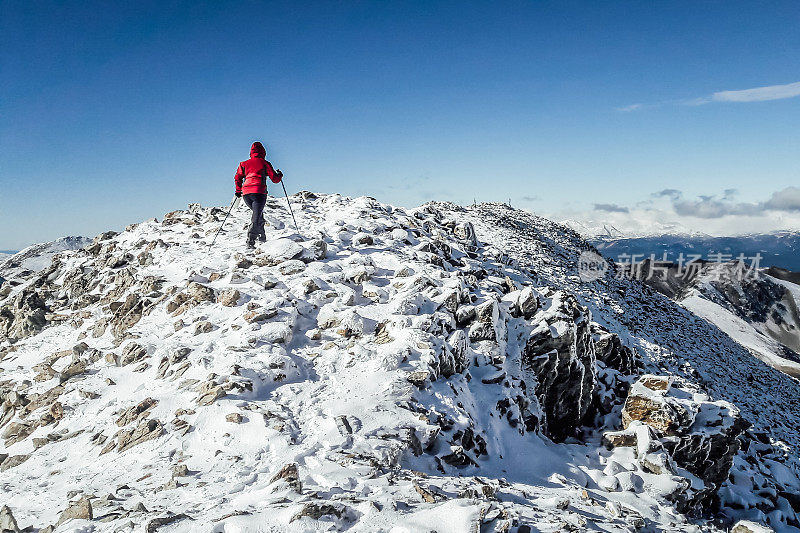 从后面看，女登山运动员正在攀登一座雪山，在天空的衬托下