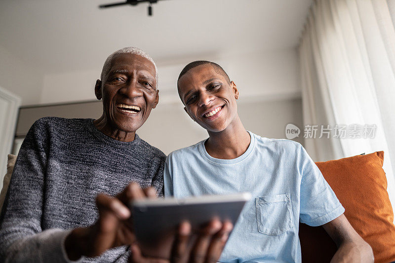 爷爷和孙子在家里使用数字平板电脑的肖像