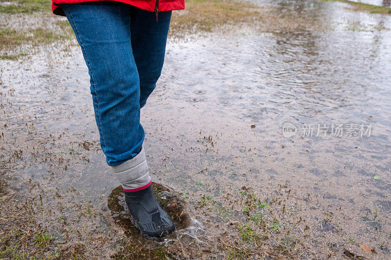 在室内天气，穿着近距离靴子的雨脚正踩在高水位的脚上。过马路。