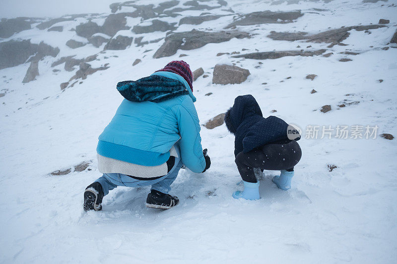 两岁的孩子和他的妈妈在雪地里玩耍