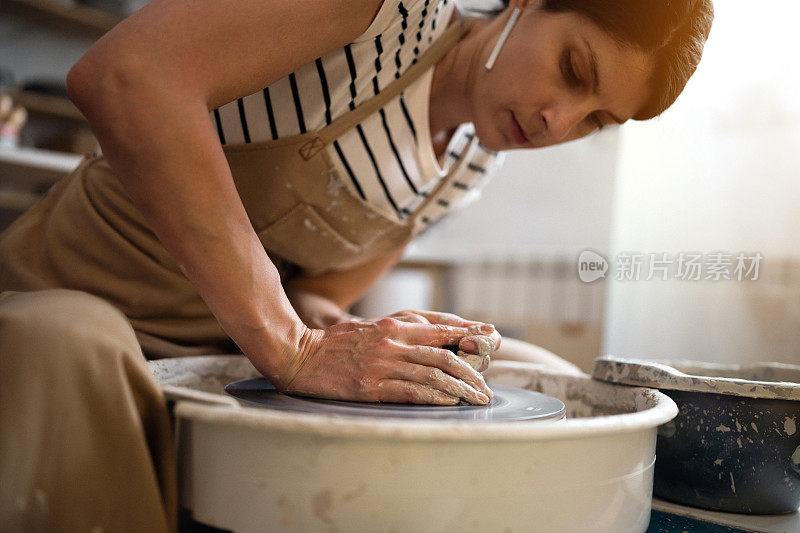 一位年轻的妇女在她的作坊里用陶轮工作