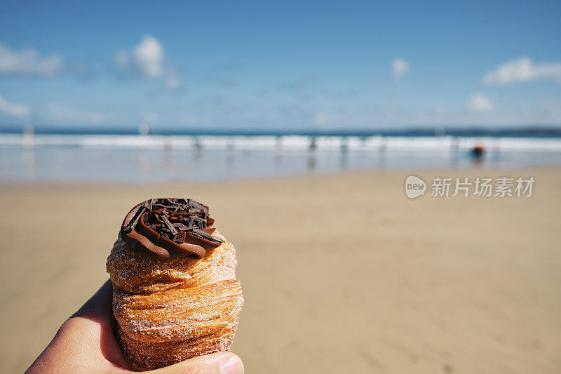 在康沃尔郡纽基的托万海滩，一个明媚的6月的一天，一只手拿着美味的克芬。