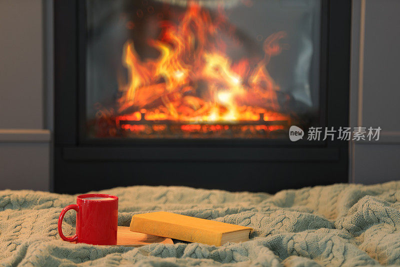 在壁炉旁的针织毯上放上一杯热饮和书，留出文字空间。舒适的氛围