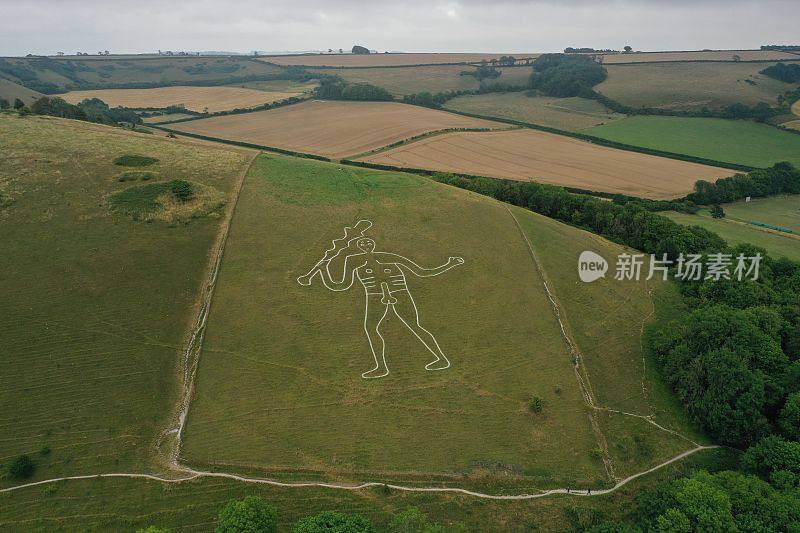 无人机拍摄的塞内·阿巴斯巨人，一个人影矗立在英格兰塞内·阿巴斯村附近的青山上