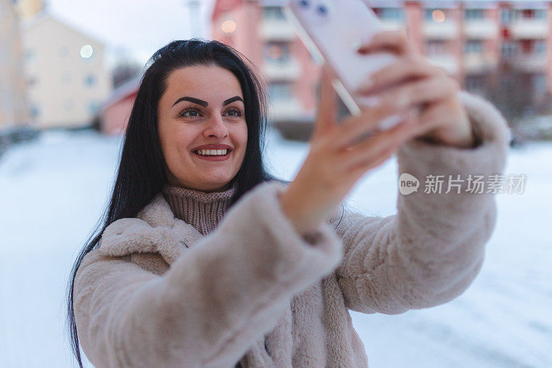 一名年轻女子在户外雪地里通过视频电话打电话