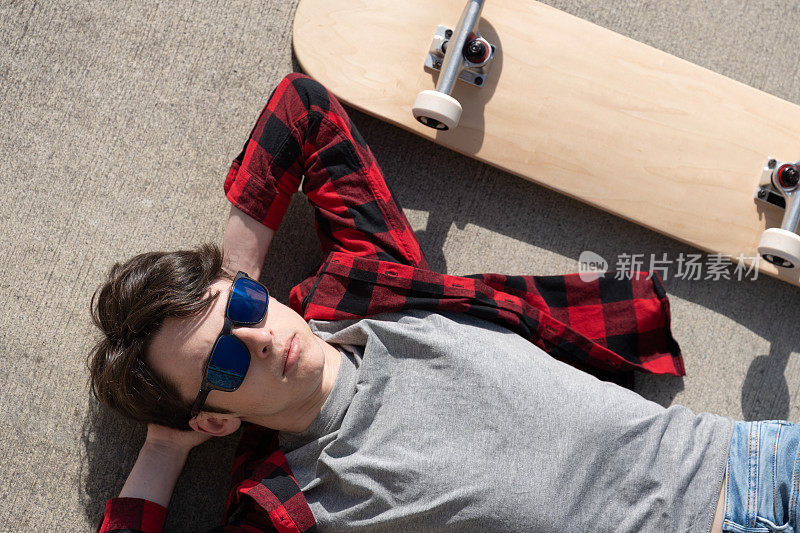 俯视图的青少年滑板男孩躺在地板上