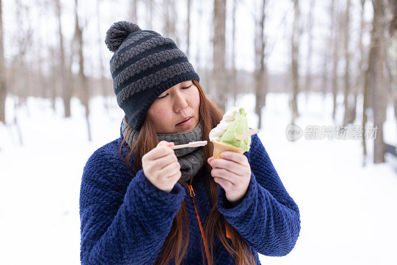 一名日本妇女在冬天吃抹茶和朗姆酒葡萄干冰淇淋