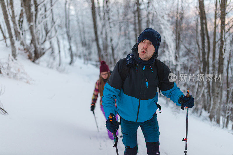 年轻英俊的男性徒步旅行者和他的女性朋友一起爬上雪山