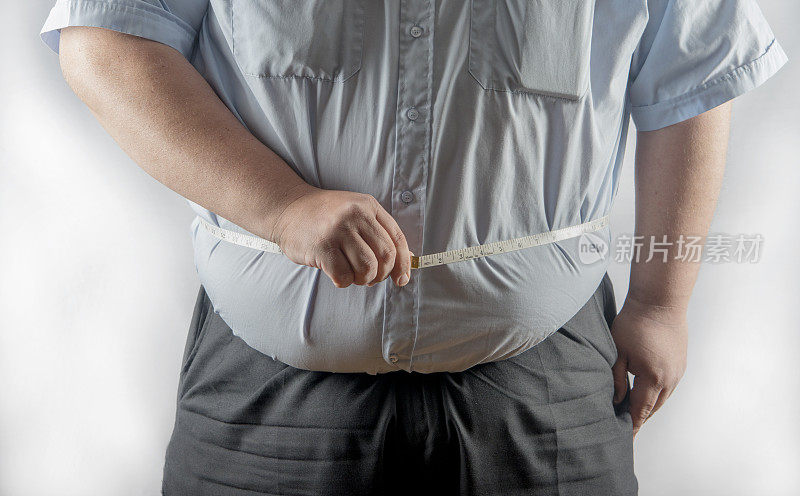 一个肥胖的男人在测量他的腰围