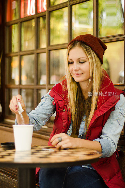 年轻女子在咖啡里加糖