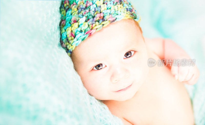 微笑的婴儿与编织帽子上的毯子