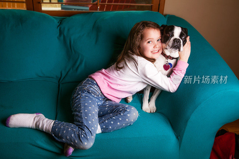 懒洋洋的6岁女孩拥抱她的拳击手狗