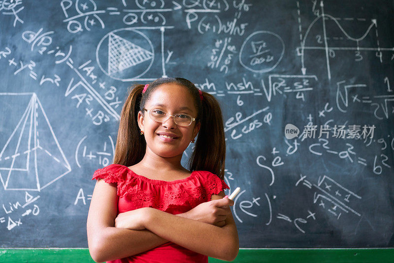 肖像快乐的女孩在黑板上解决复杂的数学问题