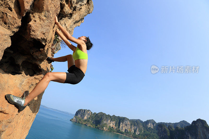 一名年轻女子攀岩者正在海边的山上攀岩
