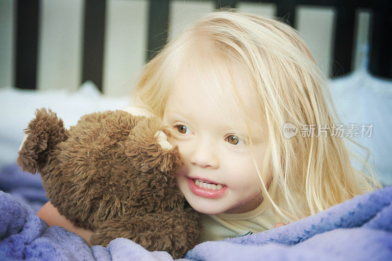 小女孩在床上抱着玩具熊