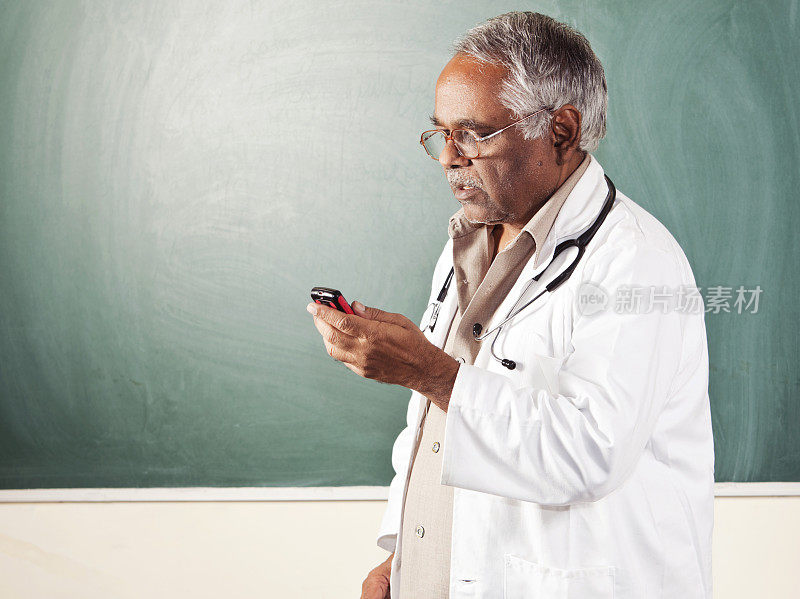 印度教授拿着手机站在黑板前