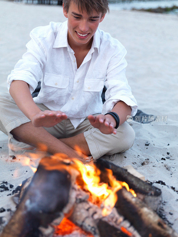 一个年轻人在海滩上享受篝火