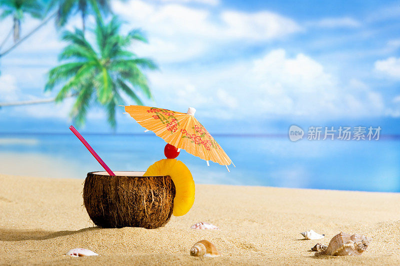 坐在沙滩上的椰子壳里的热带饮料