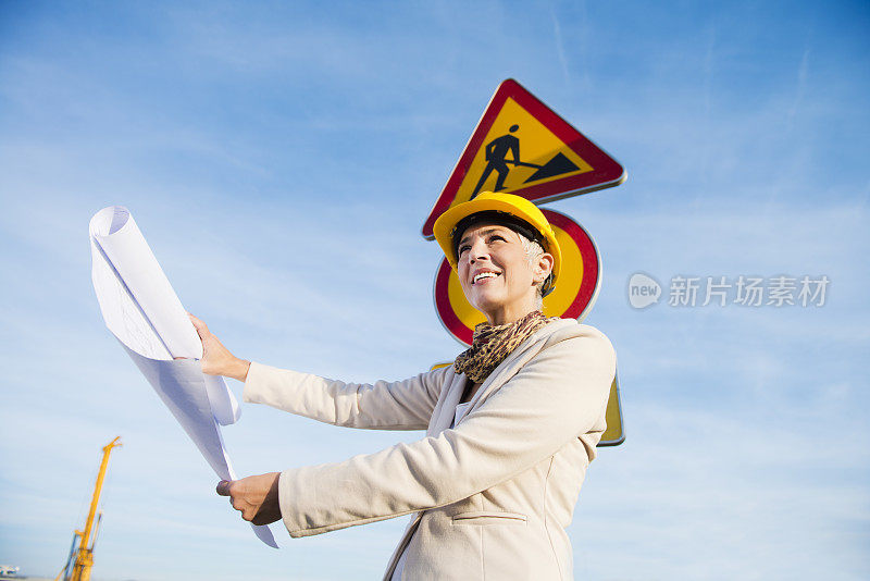 成熟的女人像建筑师一样站在路标前