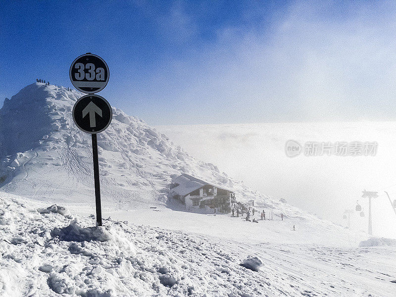 冬季滑雪场，滑雪者在背景中，云层之上的景色