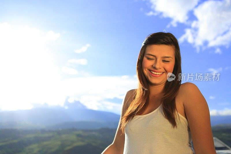 年轻女士摆出微笑的姿势看着身后的太阳