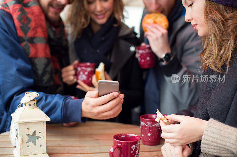 在冬天的城市里，朋友们在户外喝热饮。