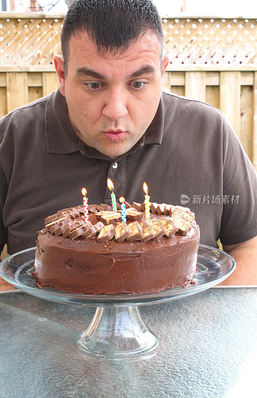 一个男人吹灭了生日蛋糕上的蜡烛