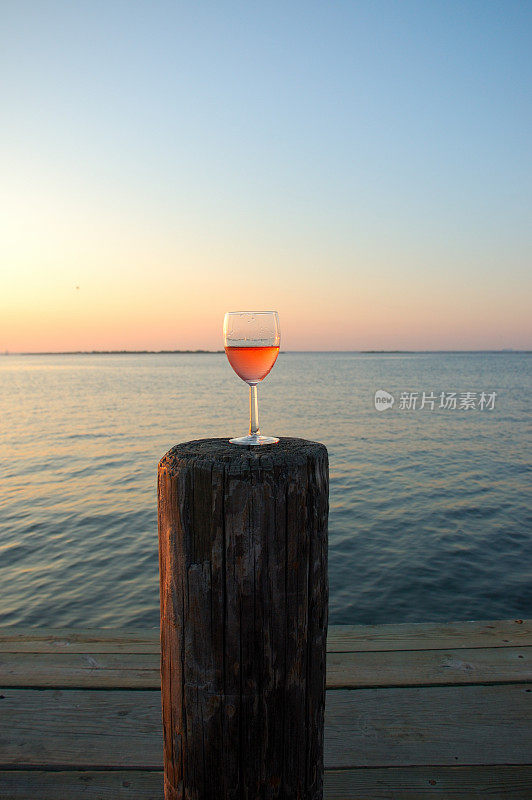 日落时分，海湾码头上的玫瑰酒满杯