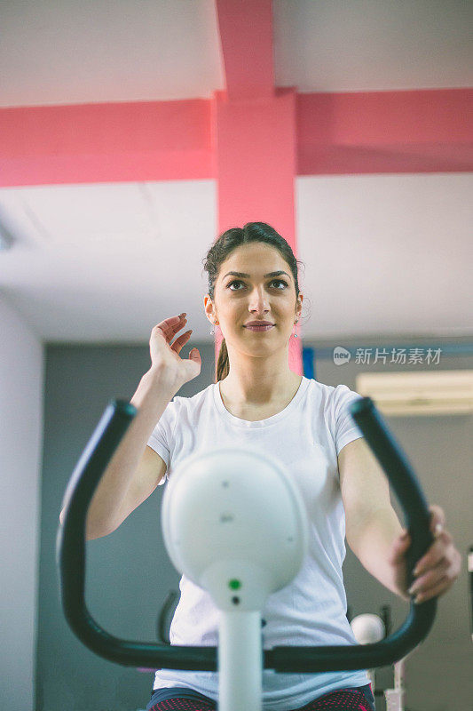 运动女人在一个健身俱乐部训练自行车-运动女孩在一个健身房的自行车上旋转