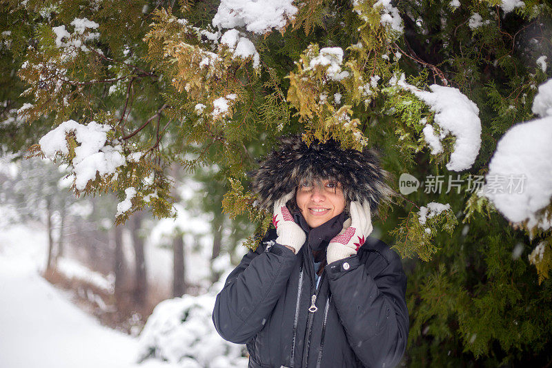 冬天的女人在寒冷的冬日里，在雪地里仰望着快乐的微笑。