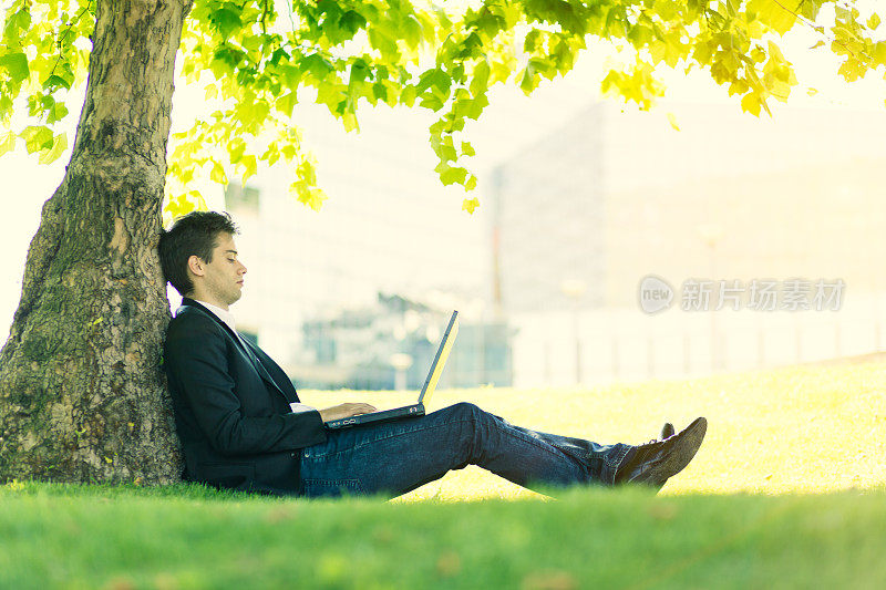 商人在一个阳光明媚的日子里在公园里使用笔记本电脑