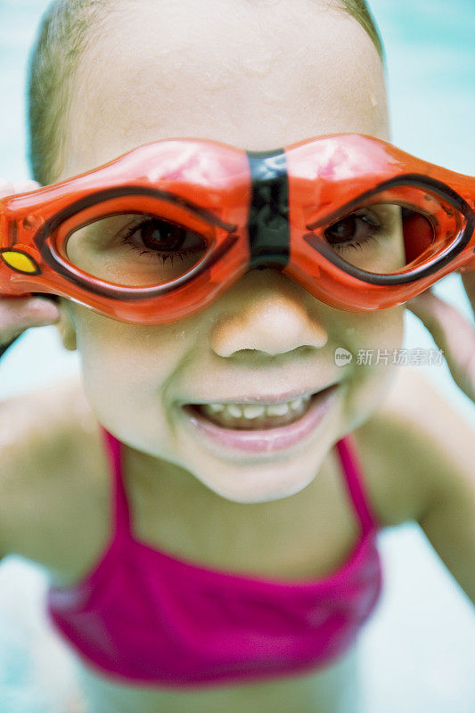 小女孩戴着护目镜在游泳池里