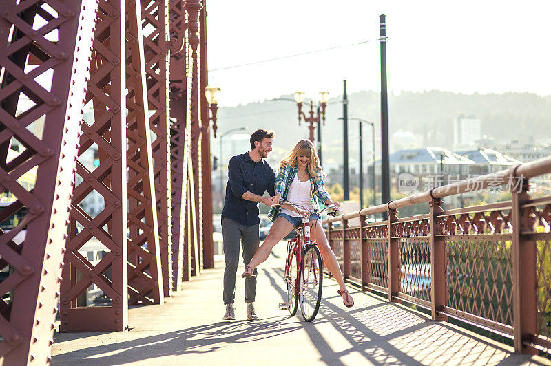 一对可爱的异性情侣骑着自行车过桥