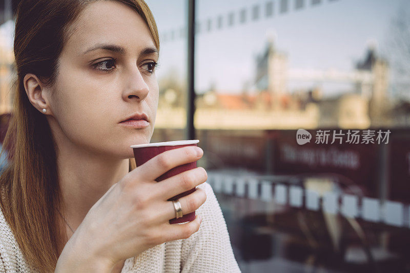 在伦敦的建筑露台上，拿着咖啡杯的体贴女人