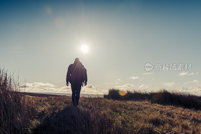 男人在秋日的阳光下徒步旅行。