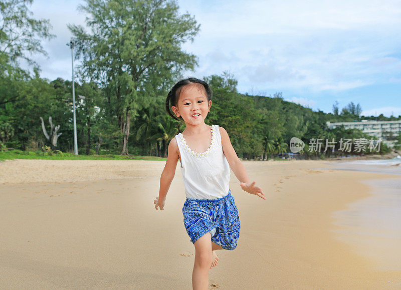 一个亚洲小女孩在海滩上跑步。