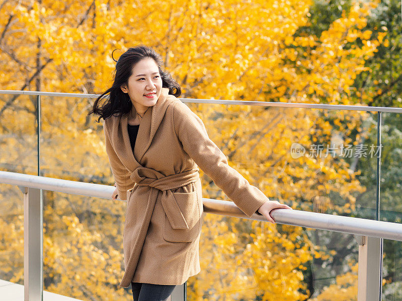 一个美丽的中国女孩的肖像站在金秋森林的背景。