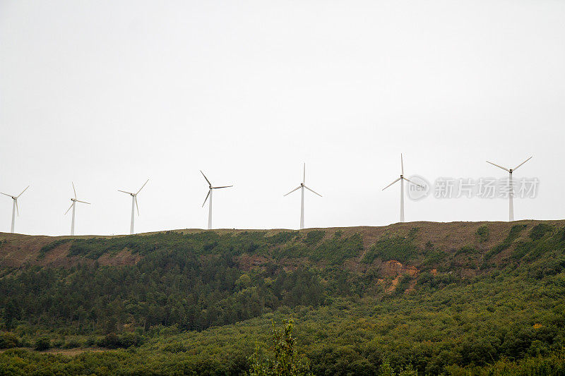 一排风力涡轮机坐落在山顶上