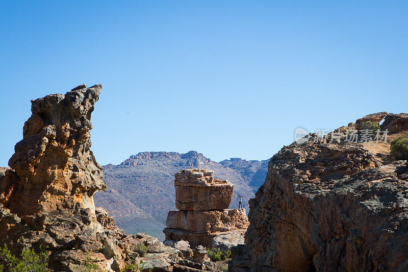 一名男子伸开双臂站在岩石上