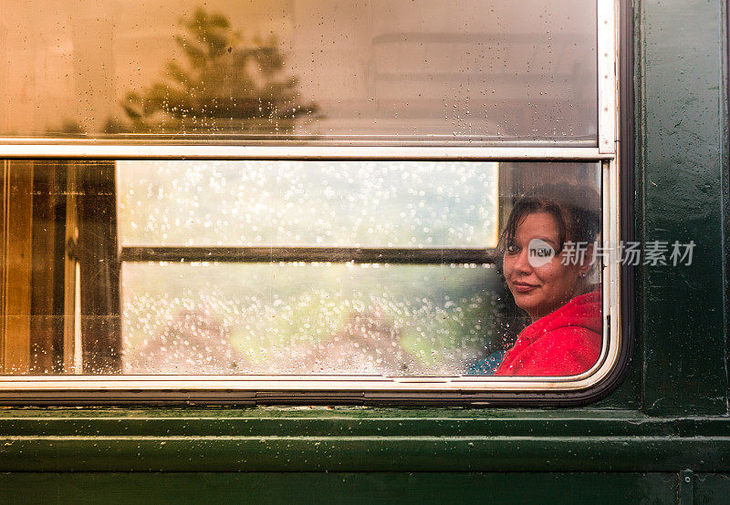 微笑的年轻女乘客看着窗外的雨滴